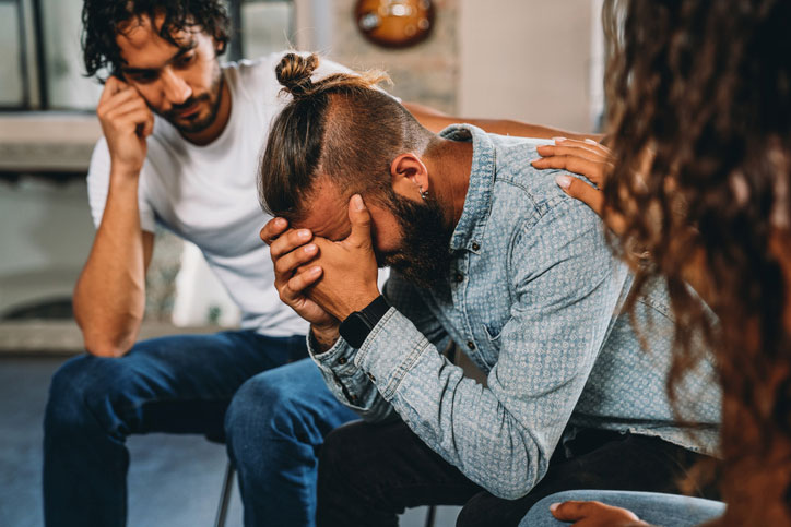 man breaking down, surrounded by help