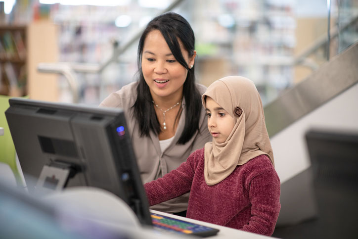 library social worker helping muslim girl on computer